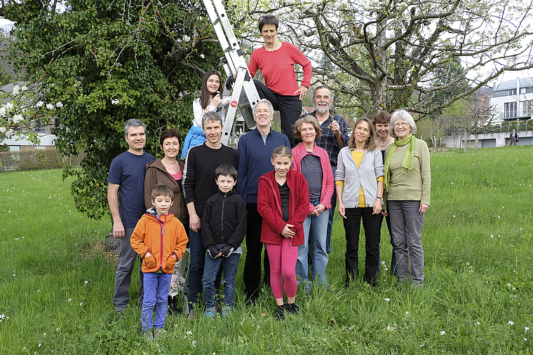 Familiäre Atmosphäre: Mitglieder der Trägerschaft Obstbaumgarten Badhof vor einem mit Efeu bewachsenen Baum.
