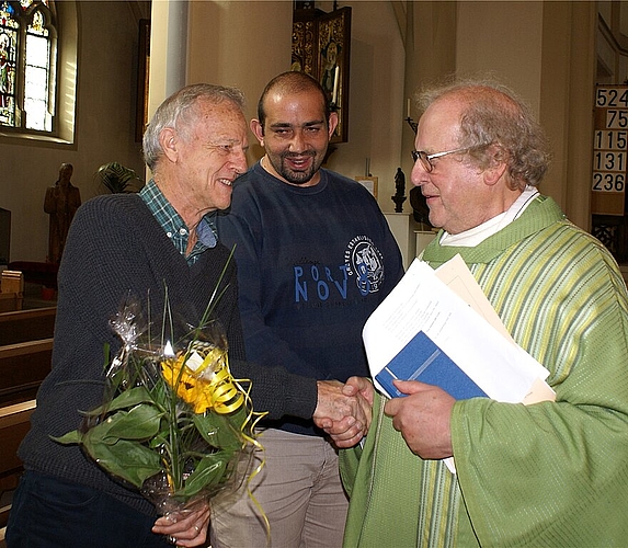 Pfarrer Franz Kuhn gratuliert zum 10-Jahr-Jubiläum: Organist David Rumsey (l.) und Hilfssakristan Vito Ferrara.