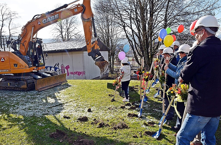 Spatenstich mit vereinten Kräften: Vertreterinnen und Vertreter von Schule, Gemeinde und Totalunternehmung lassen sich vom Bagger zum Graben herausfordern. Foto: Roland Bürki