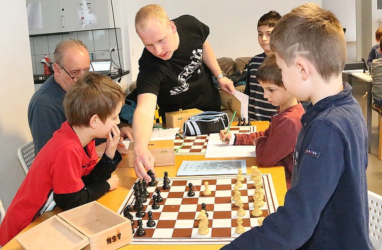 Züge zeigen und Ruhe einfordern: Peter Hug (Mitte) hat mit den Schachkindern alle Hände voll zu tun. Fotos: Gini Minonzio
