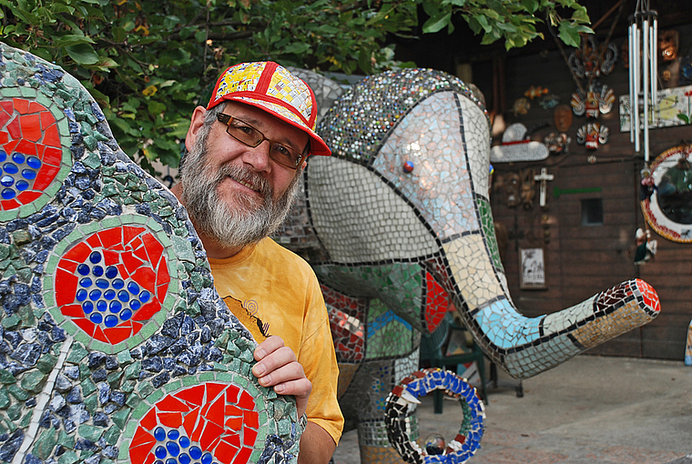 Glitzernd und farbenfroh: Markus Moser zwischen seinen Figuren. Foto: Thomas Brunnschweiler