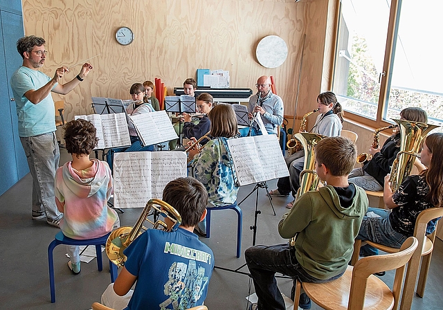 Blasmusikunterricht für alle: Mit Dirigent Martin Altenbach, Lehrer Marc Schwald (hintere Reihe, 3. v. l.) sowie den Schülerinnen und Schülern (vier sind an diesem Tag abwesend). Foto: Martin Staub