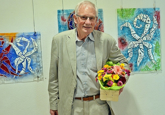 Verdiente Blumen für sympathischen Künstler: Emil «Migger» Simonetti vor seinen «beglückten und swingenden» Laufen- und Liestal-Stäben in Glasfusing. Foto. Roland Bürki