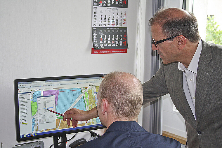 Orientierung per Bildschirm: Gemeindepräsident Giorgio Lüthi (rechts) und der vonseiten Bauverwaltung zuständige Projektleiter Harald Puchrucker bei der Arbeit mit dem Münchensteiner GIS. Foto: ZVG