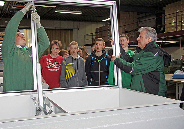 Geschlechtertrennung: Die Mädchen überlassen die erste Reihe den Jungs, die arbeiten, handlangern wie Kurt Röschli (r.) oder zumindest interessiert bei der Montage der innovativen Rauchschutzkuppel zuschauen.  Foto: Gini Minonzio