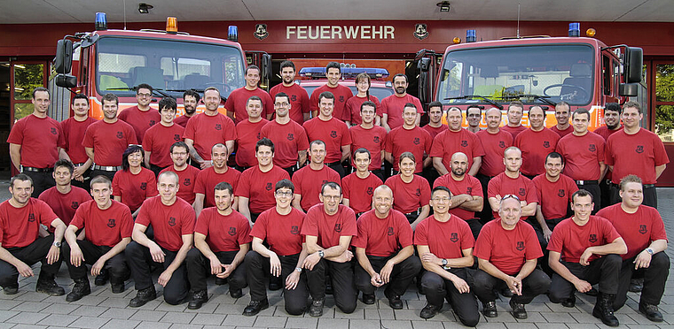 Mannschaftsfoto: Die Münchensteiner Feuerwehr im «Arbeitstenue», im Hintergrund die Einsatzfahrzeuge. Foto: ZVG