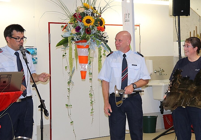 <em>Ehrung: </em>Major Markus Burger (l.) dankt Michael Henz für seine 26 Dienstjahre. Feuerwehrfrau Michaela Léchenne überreicht das Geschenk.Fotos: Gaby Walther
