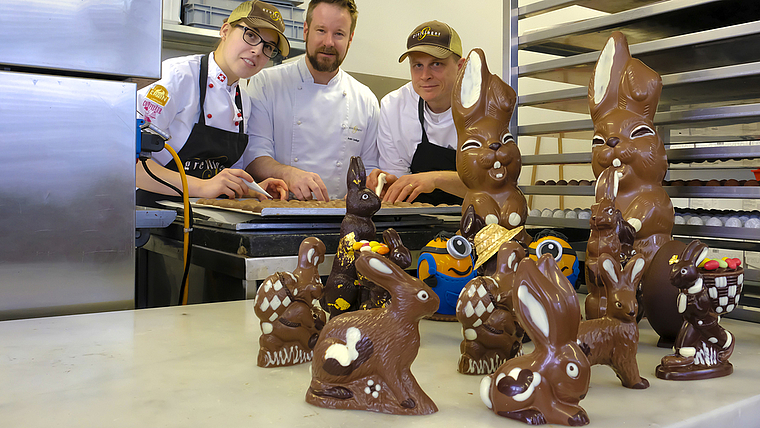 Diese Langohren aus Schokolade sind im Kägen entstanden: Dahinter die «Hasenzüchter» Sabine Häring, André Grellinger und Philippe Barthoulot (v. l.) von der Confiserie Grellinger. Foto: Thomas Brunnschweiler