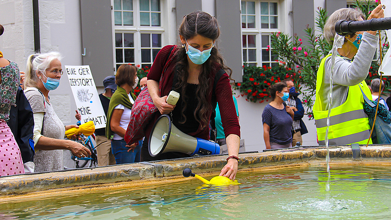 Symbolischer Akt: Jennifer McGowan, Sprecherin der Initiative Natur- und Kulturraum Dornach-Arlesheim, füllt ihre Giesskanne am Brunnen des Domplatzes.  Foto: Tobias Gfeller