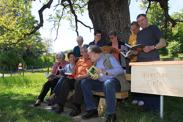 Romantik: Das Team der Bücherbrockenstube und Burgerrat Josef Marquis (rechts) weihen die Lesebank ein. Foto: Gini Minonzio