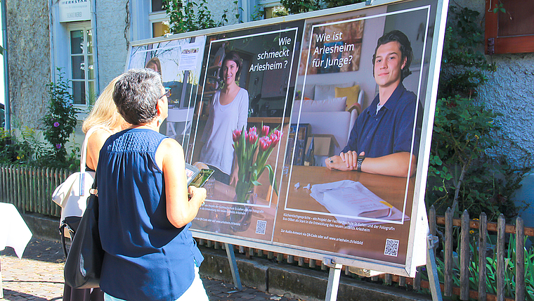 Küchentischgespräche: Mit dem Handy kann man den QR-Code auf den Plakaten im Dorfkern scannen ,um den acht befragten  Arlesheimerinnen und Arlesheimern zuzuhören. Foto: Tobias Gfeller 