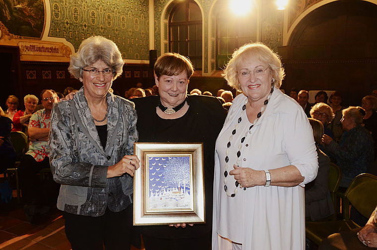 Preisübergabe: Therese Mathys (l.), Mitglied der Kulturkommission der Bürgergemeinde, übergibt den «Münggestei» in Form eines Gemäldes von Ivan Grill an Meta Zweifel (Mitte), daneben Laudatorin Julia Onken. Foto: Heiner Leuthardt