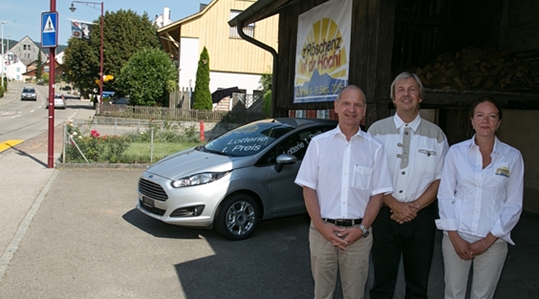 Die Drahtzieher und der Tombola-Hauptpreis: Simon Imhof, OK-Präsident, Remo Oser, Gemeindepräsident, und Nadine Steiner, Programmverantwortliche (v.l.). Im Hintergrund das von der einheimischen Dorfggarage gestiftete Auto, unter dem Logo zum Fest.