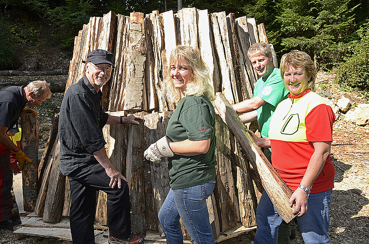 Aufbau des Holzkohlenmeilers: Kreisförster Christian Gilgen, die Assistentin der Köhlerin, Heidi Moy, den Revierförster Christian Becker sowie die Köhlerin Doris Wicki (v. l. ). Foto Heiner Leuthardt