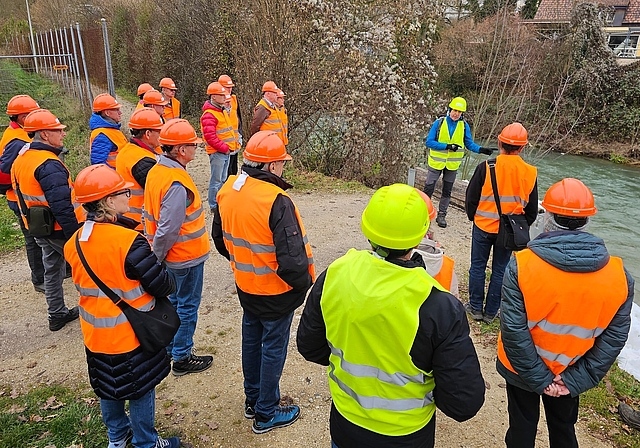 Draussen unterwegs: Ruedi Hofer (hinten in Gelb) führte die Gruppe auch an den Ort des Geschehens und machte so die bereits durchgeführten und die geplanten Massnahmen greifbar. Hinter der Eishalle ist ein Ersatz für den Norimattsteg geplant.