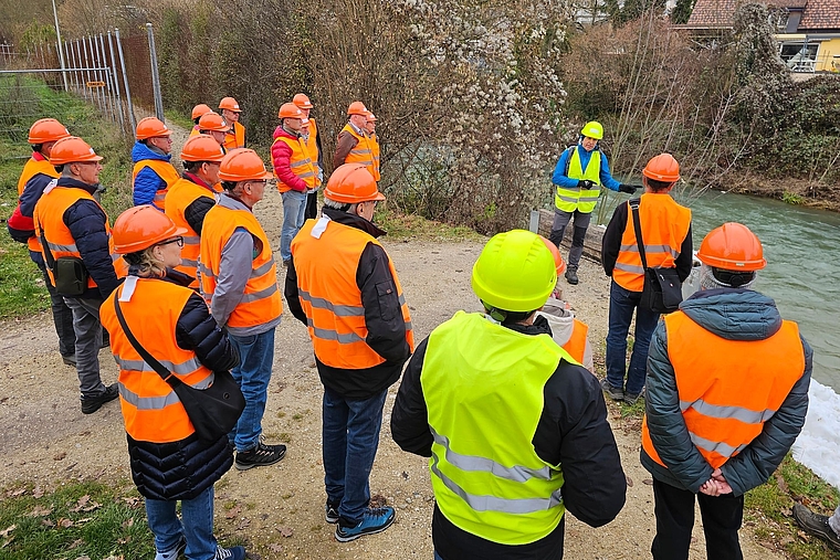 Draussen unterwegs: Ruedi Hofer (hinten in Gelb) führte die Gruppe auch an den Ort des Geschehens und machte so die bereits durchgeführten und die geplanten Massnahmen greifbar. Hinter der Eishalle ist ein Ersatz für den Norimattsteg geplant.