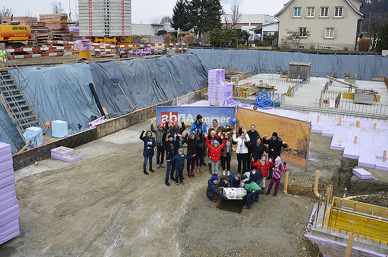 In der Baugrube: «Fokus»-Schulkinder platzieren eine mit persönlichen Gegenständen gefüllte Holzkiste in die Bodenöffnung.  Foto: Thomas Kramer