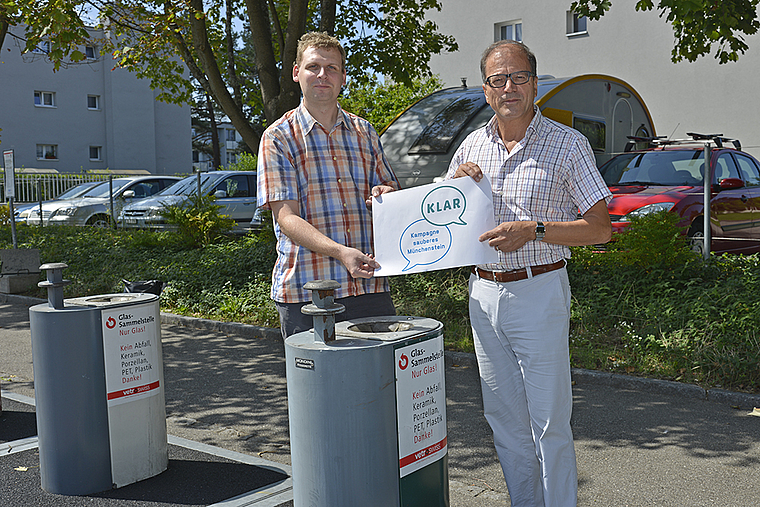 Kampagnestart: Münchensteins Gemeindepräsident Giorgio Lüthi (l.) und Projektleiter Florian Inneman präsentieren das «KLAR»-Logo vor der Unterflur- Wertstoffsammelstelle Lärchenstrasse-Grubenstrasse. Foto: ZVG