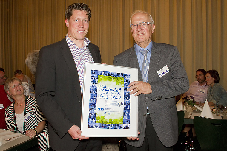 Abschiedsgeschenk: Michael Dreier, frischgebackener Präsident des Vereins Gewerbe und Industrie Aesch, übergibt dem frischgebackenen Ehrenpräsidenten Roland Hohl eine Rebpatenschaft mit dem passenden Namen «Clos du Roland». Foto: ZVG/Claudia Sc