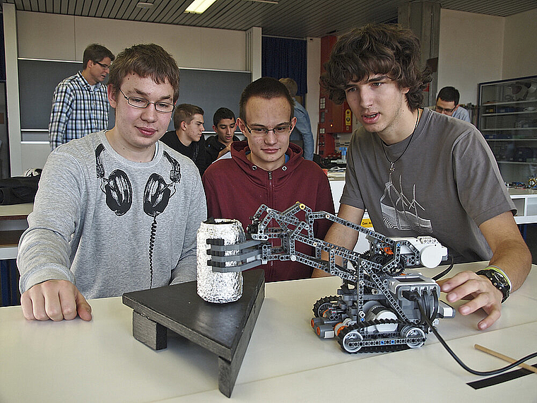 Greifroboter an der Arbeit: v. l. Martin Saladin, Philipp Neth, Michel Vögtli. Die drei bauten die Maschine, die den Linien entlang fährt und am Ende eine mit Alu eingepackte Colabüchse greift und hievt. Foto: Tobias Gfeller