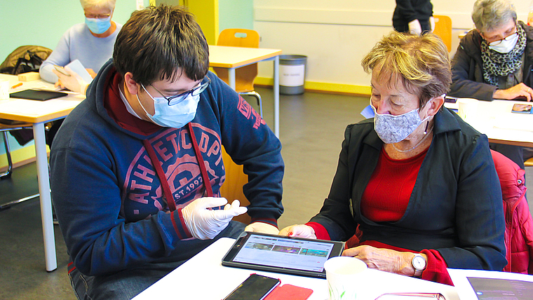 Neue Technologie kennen lernen: Ein Schüler bringt der Seniorin die SBB-App näher. Foto: Tobias Gfeller