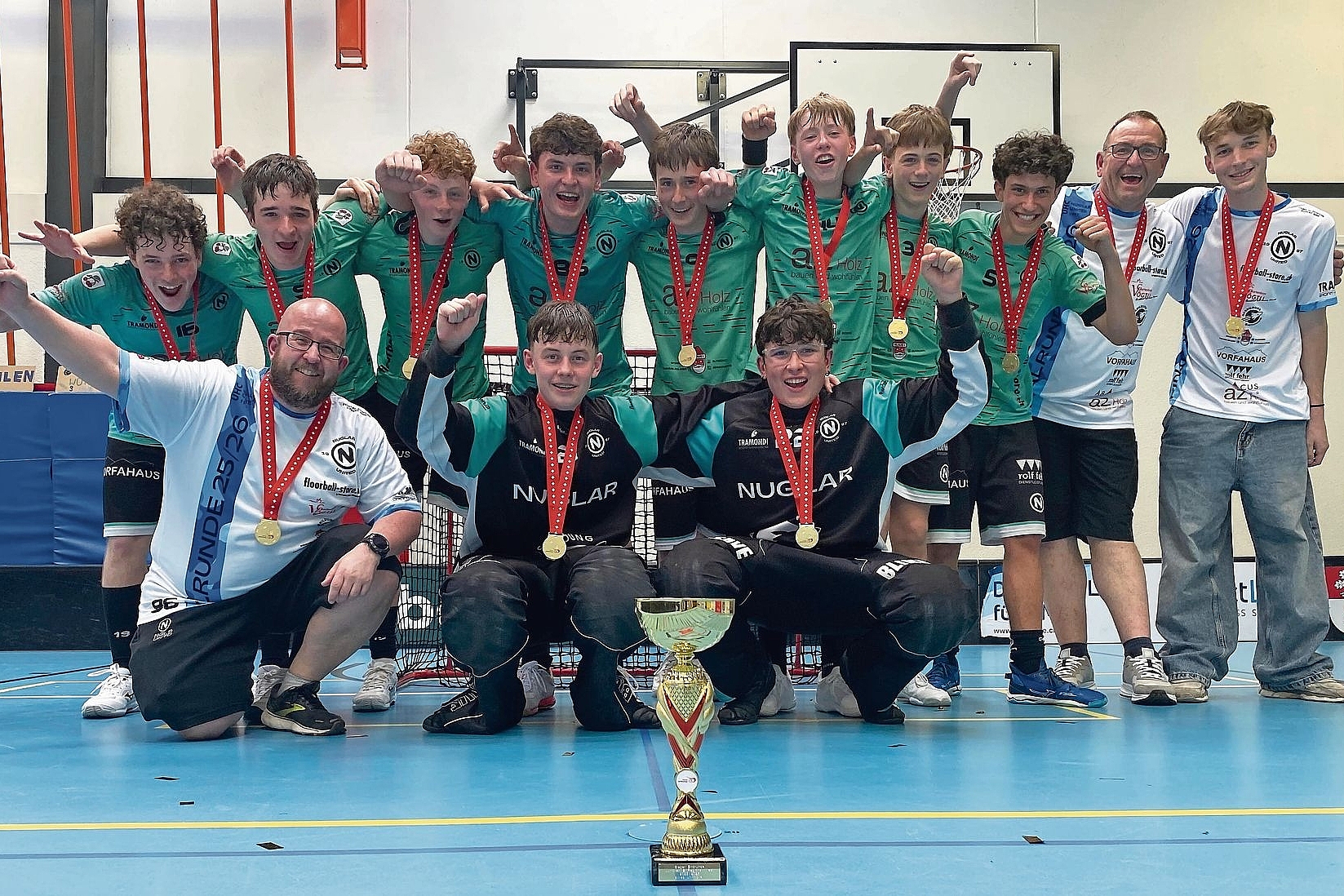 Ganz oben auf dem Podest: Jubel bei den Junioren B des UHC Nuglar United. Sie sind der Schweizer Meister West der Saison 2025/2026. Ebenfalls im Bild (weisse Shirts, von links): ihre Trainer Christian Häusler, Patrick Gruner und Niilo Pflugi. Fotos: UHC Nuglar United