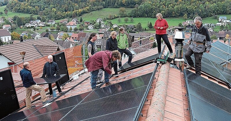 Montieren der Photovoltaikanlage: Florin Schaffner, Projektleiter von der Energiewendegenossenschaft Basel (Mitte, rote Jacke), die Bauherrschaft Susanne Koch und Martin Hauser (rechts) und Mithelfende. Foto: Gaby Walther