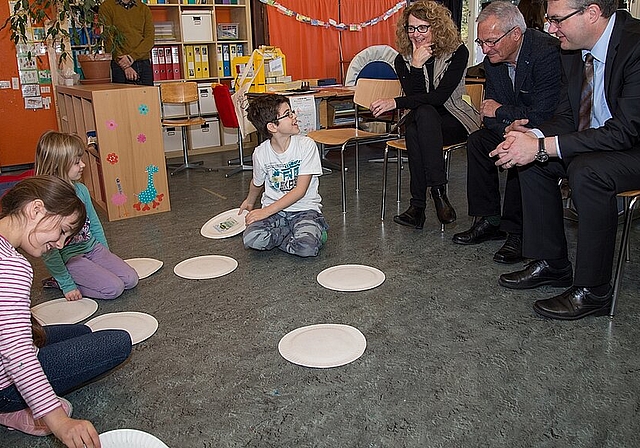 Kinder spielen Abfall-Memory: Die Gäste Bildungsdirektor Remo Ankli, Josef Christ, Esther Grond (v.r.) und Marco Maurer (im Hintergrund) schauen interessiert zu. Fotos: Martin Staub 
