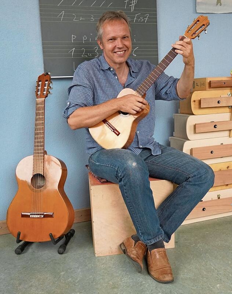 In der Hand eine Cuatro, links daneben eine gewöhnliche Gitarre: Berni Hager demonstriert den Unterschied zwischen den beiden Instrumenten. Foto: Tobias Gfeller