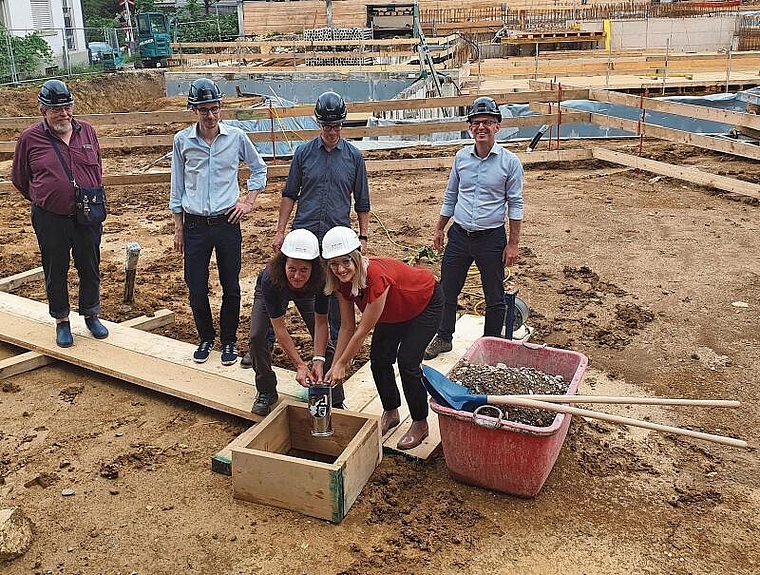 Versenken die Zeitkapsel: (v.l.h.) Gemeinderat Jürg Seiberth, die Architekten Oliver Märki und Marco Sahli, Gemeindepräsident Markus Eigenmann; (v.l.v.) Gemeinderätin Monika Strobel und Projektleiterin Daniela Baum. Foto: Fabia Maieroni