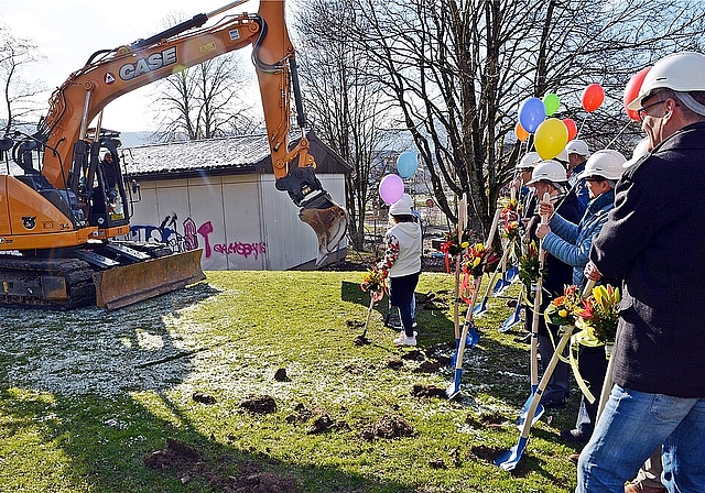 Spatenstich mit vereinten Kräften: Vertreterinnen und Vertreter von Schule, Gemeinde und Totalunternehmung lassen sich vom Bagger zum Graben herausfordern. Foto: Roland Bürki
