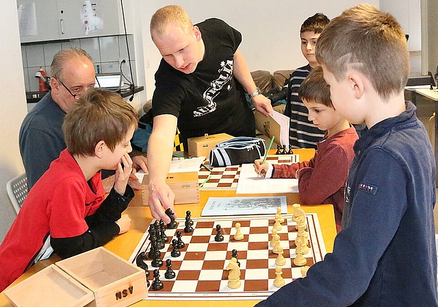 Züge zeigen und Ruhe einfordern: Peter Hug (Mitte) hat mit den Schachkindern alle Hände voll zu tun. Fotos: Gini Minonzio