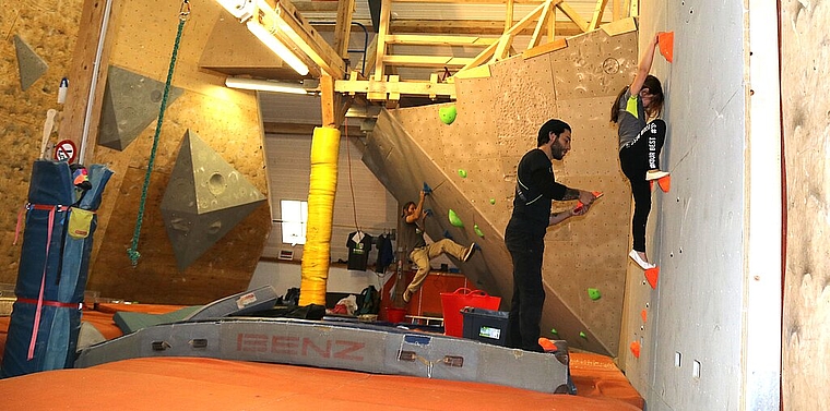 <em>Bis am Sonntag ist der Aufbau der Boulderanlage fertig: </em>Raphael Metzger (hinten) und Alessandro Esposito montieren die Griffe, Valentina testet die Abstände.Foto: Gaby Walther