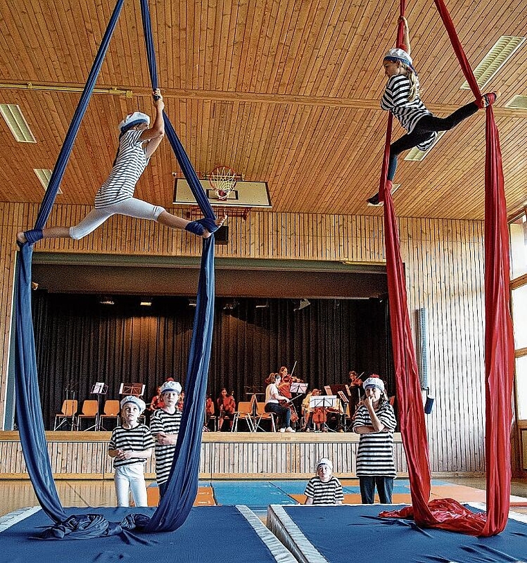 Akrobatik mit Musik: Die Turnenden der Zirkusgruppe FederBlau mit der Schiffskapelle der Musikschule im Hintergrund. Foto: Martin Staub