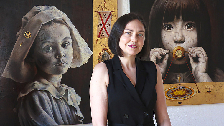 Irina Bugoslavska vor zwei ihrer Gemälde: Das Gesicht rechts stellt ihre Enkelin dar.  Foto: Thomas Brunnschweiler