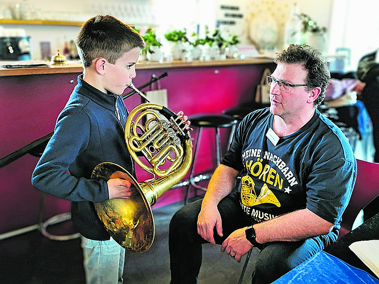 Ob es wohl das Waldhorn wird?: Ben bläst zum ersten Mal ins Instrument und lässt sich dabei von Musiklehrer José Martin Blanco instruieren. Foto: Melanie Brêchet