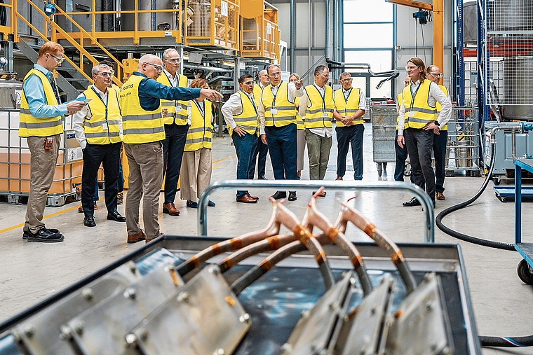 In der Industrieanlage in Büsserach: Ein Elantas-Mitarbeiter erläutert die Applikation der Primärisolierung auf Windkraft-Spulen. Foto: zVg/ Sandro Karrer