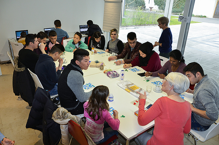 Willkommene Abwechslung im monotonen Flüchtlingsalltag: Im Pfarrhof St. Josef spielen Männer, Frauen und Kinder zusammen mit freiwilligen Helferinnen und Helfern einen Lottomatch. Foto: Thomas Kramer