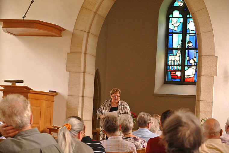 Aufmerksame Zuhörer: Meta Zweifel berichtet über die Geschichte und Geschichten rund um die Dorfkirche. Foto: Bea Asper