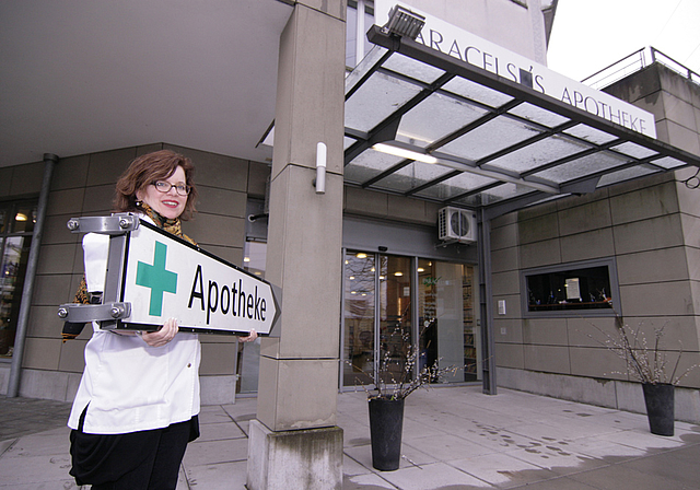 Wegweiser des Anstosses: Dieses Schild in den Händen von Paracelsus-Apothekerin Lisa Runyon wies jahrelang unbewilligt den Weg zu ihrer Apotheke – jetzt wird es von der Gemeinde Dornach nicht mehr geduldet.  Foto: Lukas Hausendorf