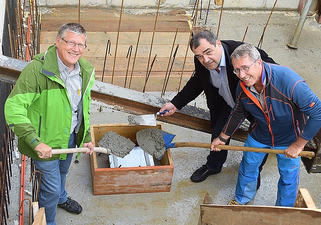 Wer wird die Kiste in Zukunft einmal ausgraben? (v.l.) Baupräsident und Gemeinderat Hugo Bürki, Gemeindepräsident Beat Fankhauser und Gemeindevizepräsident Peter Tschudin betonierten im Fundament Zeitzeugen von heute ein. Foto: Bea Asper