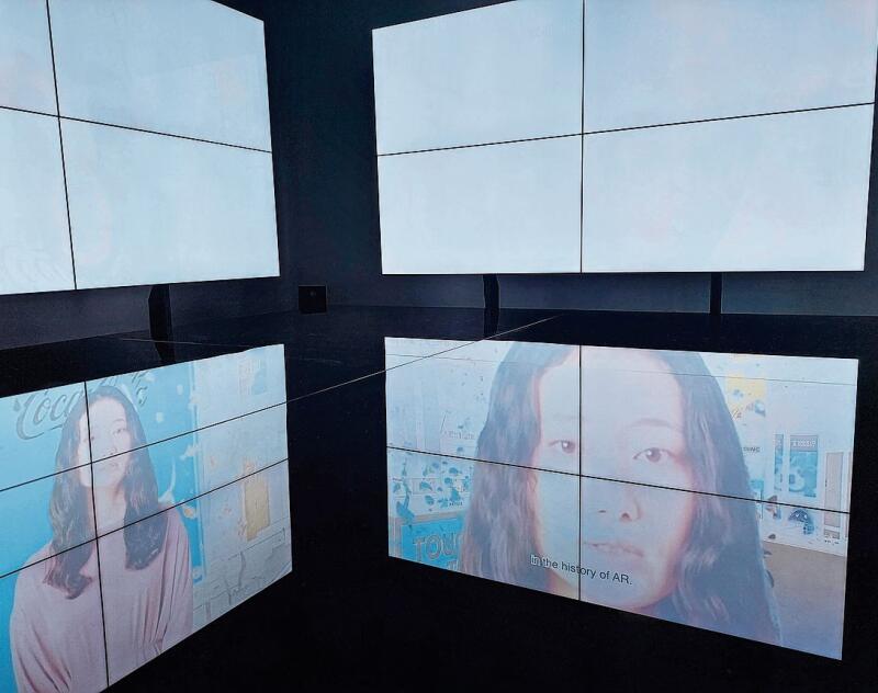 Bildschirme ohne Bildträger: Die durch künstliche Intelligenz erzeugten Videoclips werden von einer schwarzen Platte auf dem Boden reflektiert. Foto: Jeannette Weingartner