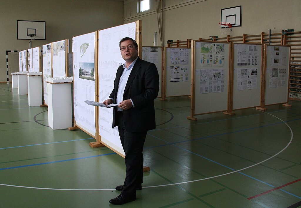 Ausstellung der Wettbewerbsarbeiten: Kantonsarchitekt Thomas Jung stellt das Siegerprojekt vor. 7 der 98 Wettbewerbsbeiträge kamen in die zweite Runde und sind noch bis zum 14. Juli in der Turnhalle ausgestellt. Foto: Gaby Walther
