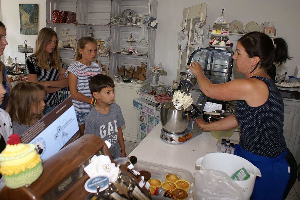 Buttercreme wird zubereitet: Angela Zuber mit aufmerksamen Kindern.