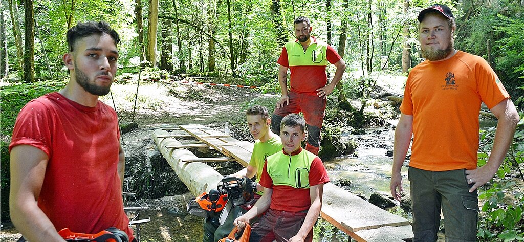 Kraftakt geschafft: Die beiden je eine Tonne schweren Tannen liegen als Brückenträger auf den Distanzhaltern der Wider- lager auf. Die Forstwarte in Ausbildung (v.l.) Janis, Nicola und Matthias, Kursinstruktor Stephan Erbsmehl und der Planer und angehende Förster Mathias Roth. Fotos: Roland Bürki
