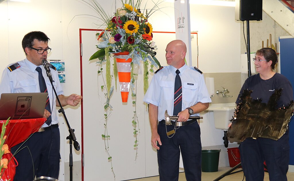 <em>Ehrung: </em>Major Markus Burger (l.) dankt Michael Henz für seine 26 Dienstjahre. Feuerwehrfrau Michaela Léchenne überreicht das Geschenk.Fotos: Gaby Walther
